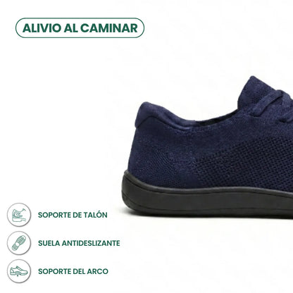 Close-up of the heel and side of a navy knit trainer on a black sole, with icons for heel, grip and arch support. 22