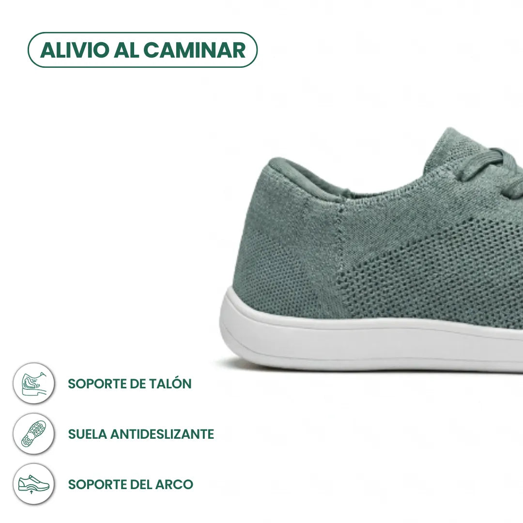 Close-up of the heel and side of a sage green knit trainer on a white sole, with icons for heel, grip and arch support. 31