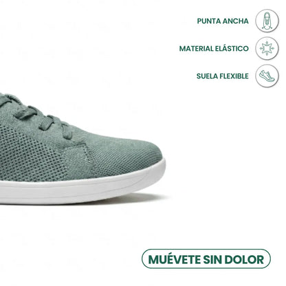 Close-up of the toe of a sage green knit trainer with white sole, with icons for wide toe, stretchy material and flexible sole. 32