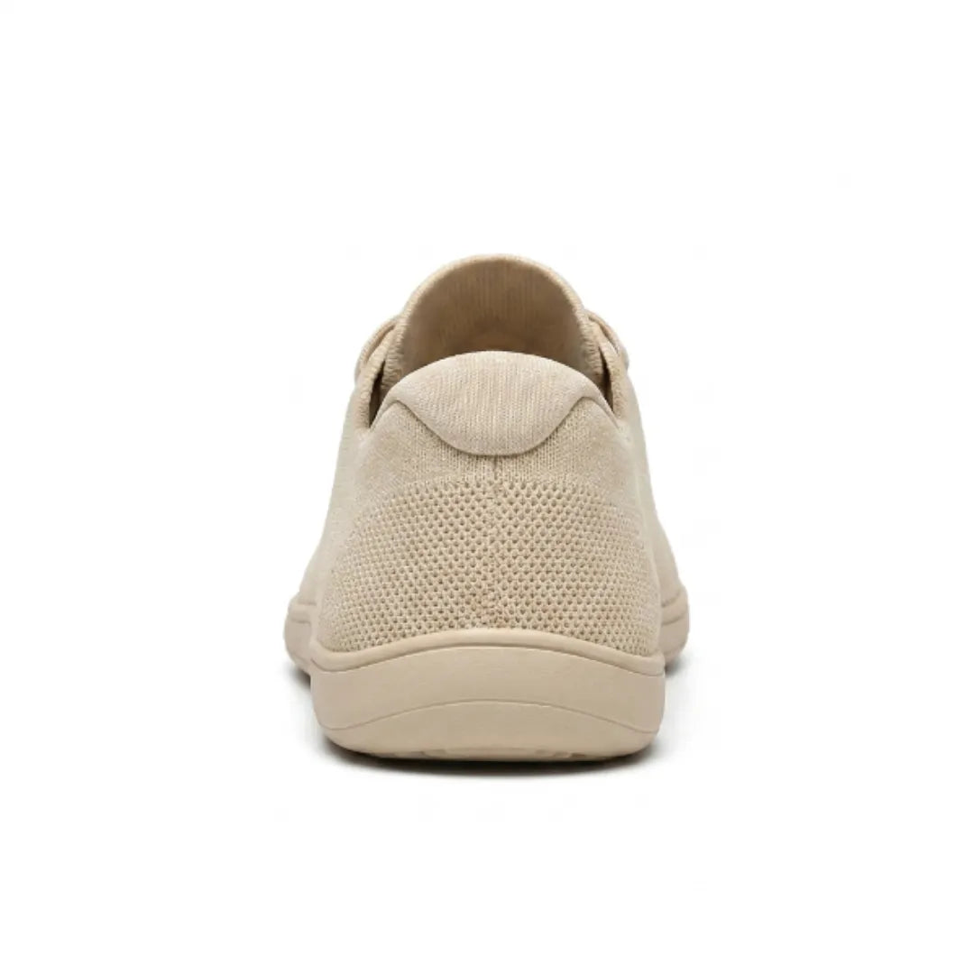 Rear view of a beige knit trainer showing the heel tab, perforated knit and flat sole. 9