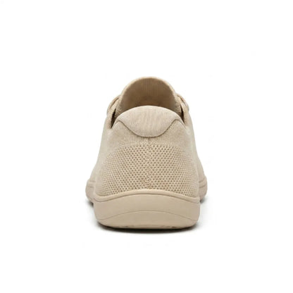 Rear view of a beige knit trainer showing the heel tab, perforated knit and flat sole. 9