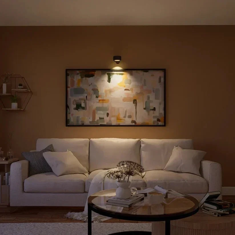 Black lamp above a large abstract painting, lighting a living room with a cream sofa 15