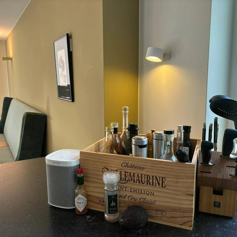 White lamp lit above a kitchen worktop with bottles, a wooden crate, a speaker and a knife block 2