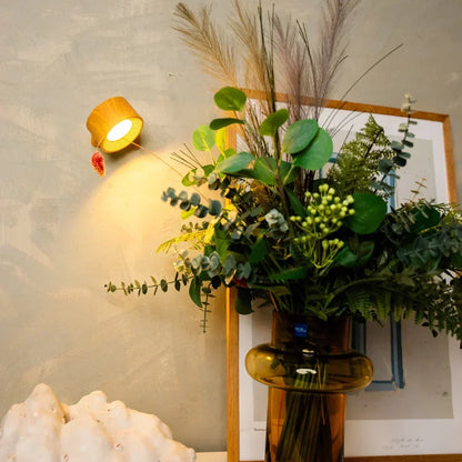 Wood-effect lamp lit on the wall above a vase of dried grasses and greenery 5