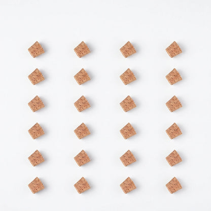 Flat lay of twenty-four tapered cork stoppers in a neat grid of six rows and four columns on a white background. 9