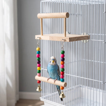 A blue budgerigar perched on the hanging swing of the wooden platform, which is attached to a white cage. 2
