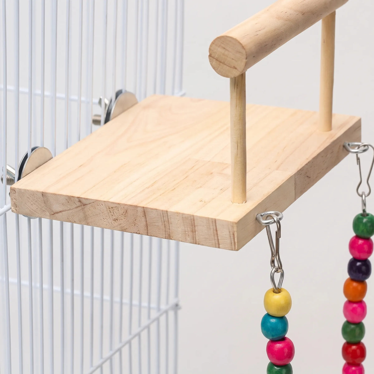 Close-up of the pale wooden platform, showing the metal discs and screws that fix it to the cage bars. 3
