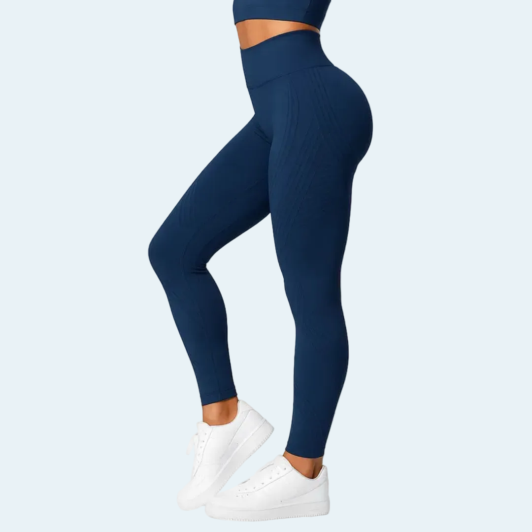 Side view of a model in navy blue high-waisted leggings and matching top, standing on tiptoe in white trainers. 4