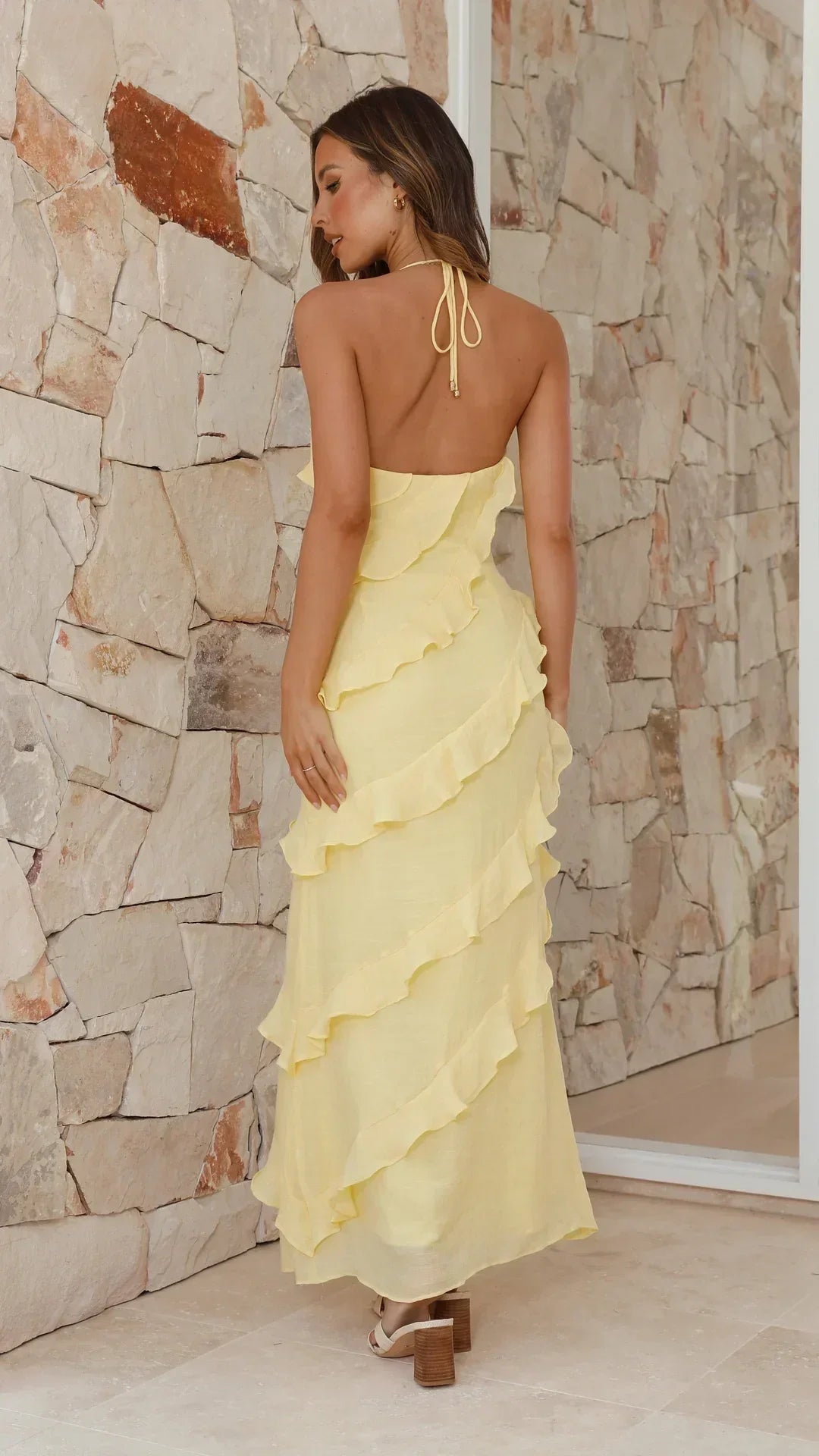 Back view of the halter dress on a model, showing the open back, tie straps and ruffled tiers 2