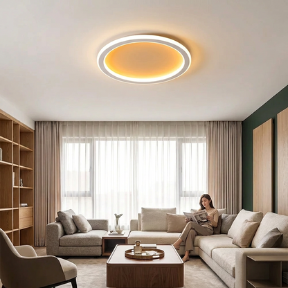 Round white ring light glowing warmly over a beige sofa as a woman reads 1