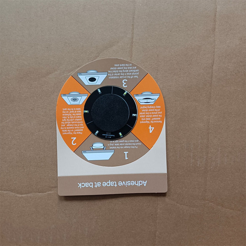 Round cardboard alignment guide on a brown box, with four numbered orange and brown panels showing the installation steps and an adhesive back. 11