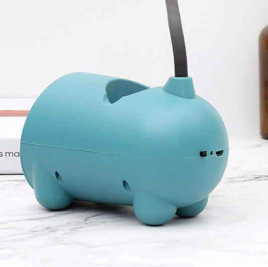 Side view of the teal lamp base with rounded feet, small holes and charging and switch openings on one end. 2