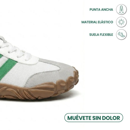 Close-up of the wide rounded toe of the white shoe with green stripe, grey suede toe cap and gum sole, with feature icons. 32