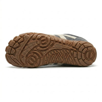 Underside of the grey shoe showing the tan rubber outsole with its deep multi-directional tread pattern. 9