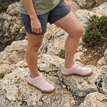 Woman in grey shorts standing on lichen-covered rocks, wearing the pink barefoot shoes with beige stripes and tan soles. 11