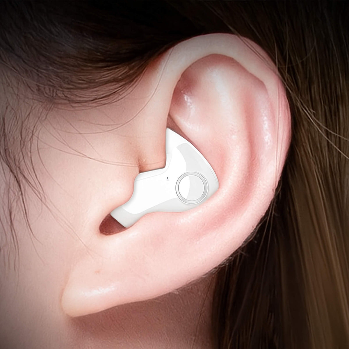 Close-up of a white earbud with a round button ring, worn in an ear 3