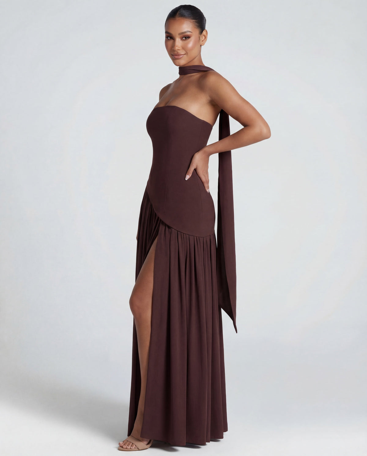 Side view of brown strapless maxi with hand on hip, showing the high slit and the scarf trailing down 4