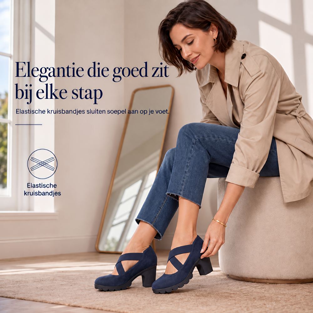 Smiling woman seated on a pouffe adjusting the strap of a navy suede-look block heel, with a mirror behind. 4