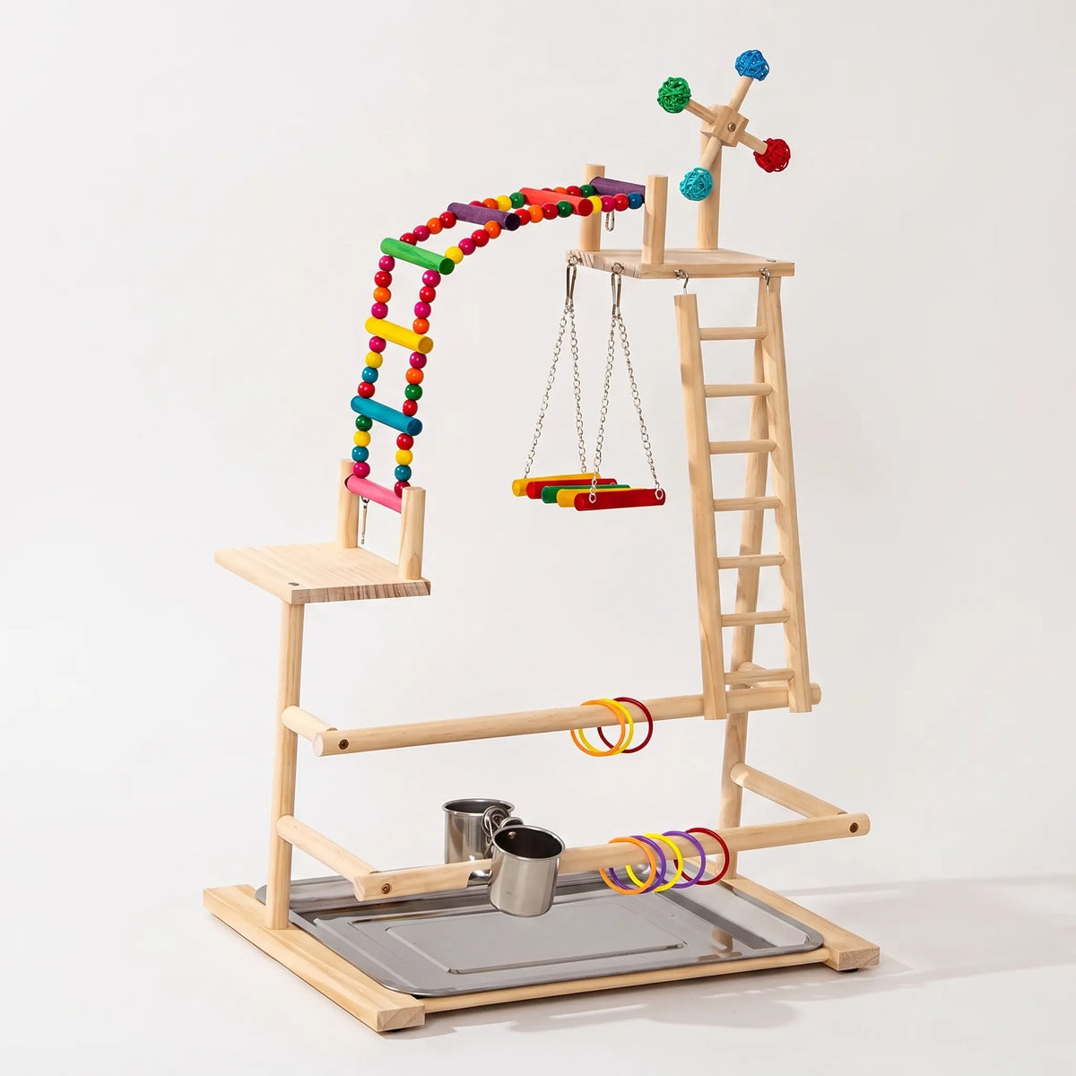 Wooden multi-level bird playground against a plain background, with a beaded rainbow ladder, swing, side ladder, spinning toy, rings, steel cups and tray. 1