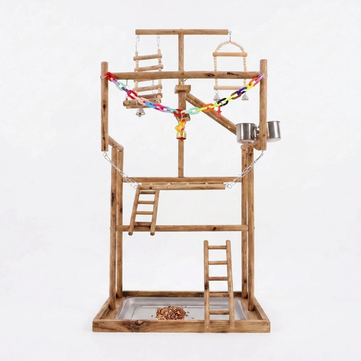 Multi-level wooden bird play stand with ladders, swings, steel cups, a colourful chain and a seed-filled tray, on a plain white background. 1