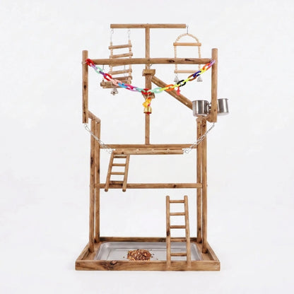Multi-level wooden bird play stand with ladders, swings, steel cups, a colourful chain and a seed-filled tray, on a plain white background. 1