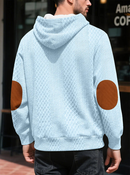 Back view of the light blue diamond-textured hoodie on a model, showing hood and elbow patches 29
