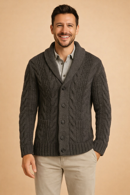 Front view of the charcoal grey cardigan on a smiling model, showing the shawl collar, cable panels, button front and ribbed pockets. 5