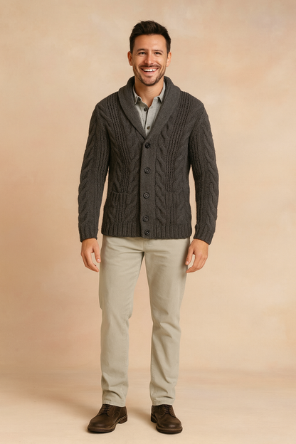 Full-length view of the charcoal cardigan worn with light stone trousers, a grey shirt and brown leather shoes on a soft beige backdrop. 6