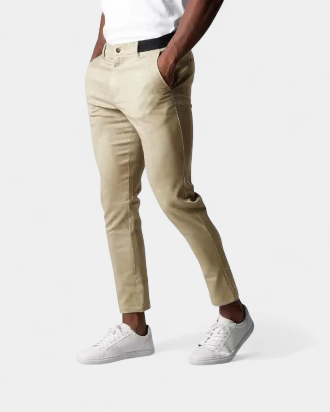 Model wearing beige slim tapered trousers with white trainers, hands in pockets, with a black elasticated waistband panel 3