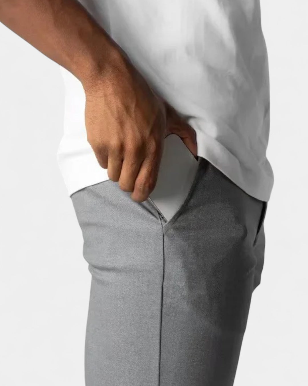 Close-up of a hand reaching into the side pocket of grey trousers, worn with a white top 6