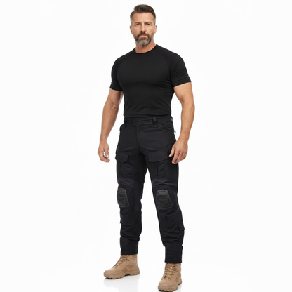 Full-length studio shot of a bearded model in a black t-shirt, the black cargo trousers and sand boots, facing the camera. 7