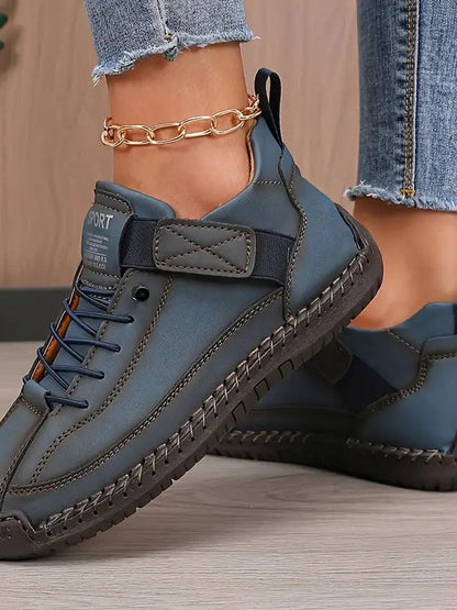 Close-up of a model wearing blue stitched trainers with elastic laces, a strap and a gold ankle chain 9