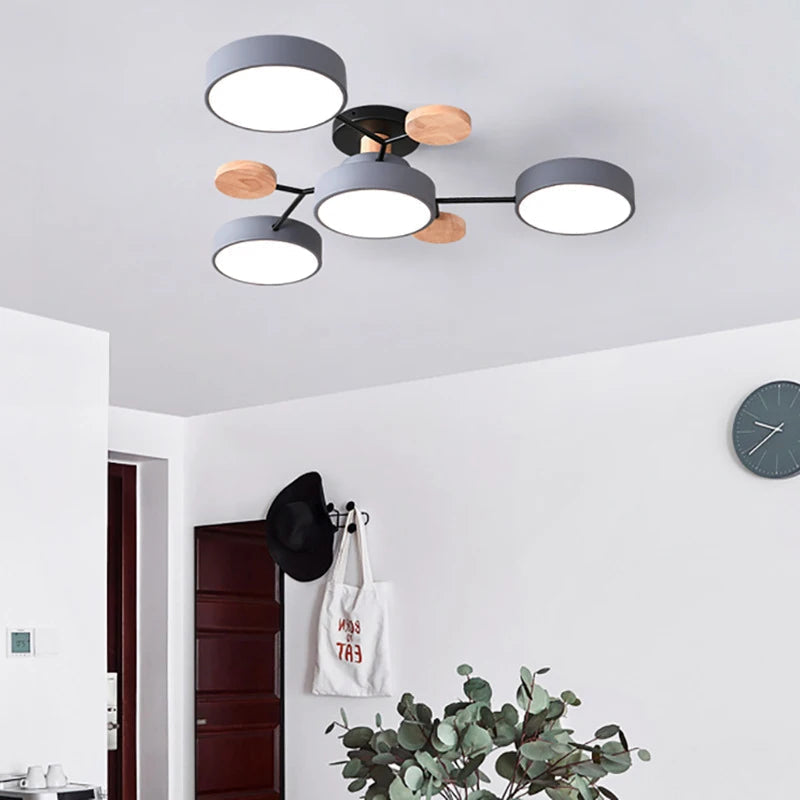 Grey four-shade ceiling light with black arms and wooden discs, hanging in a white hallway with a coat hook and wall clock. 5
