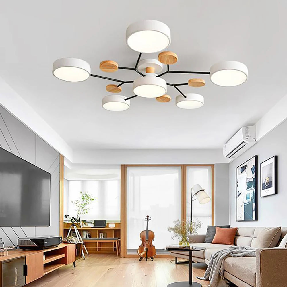 White seven-shade ceiling light with black branching arms and wooden discs, shown in a bright living room with a wooden floor. 3