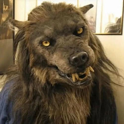 Brown furry werewolf mask with yellow eyes and bared fangs, worn by a person in a blue top, seen at a slight angle. 1