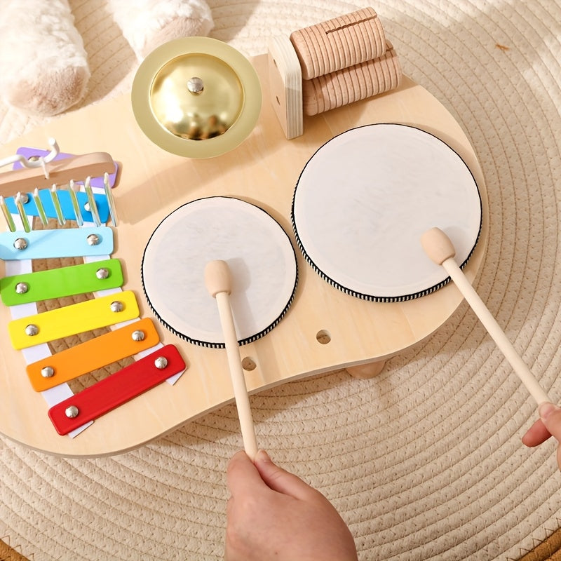 Close-up from above of a child's hands drumming on the two drums with wooden mallets, beside the xylophone and cymbal. 5
