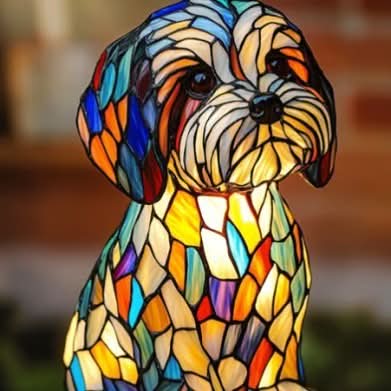 Close-up of a shaggy small-breed puppy lamp with colourful stained-glass panels and a cream beard, against a brick wall. 17