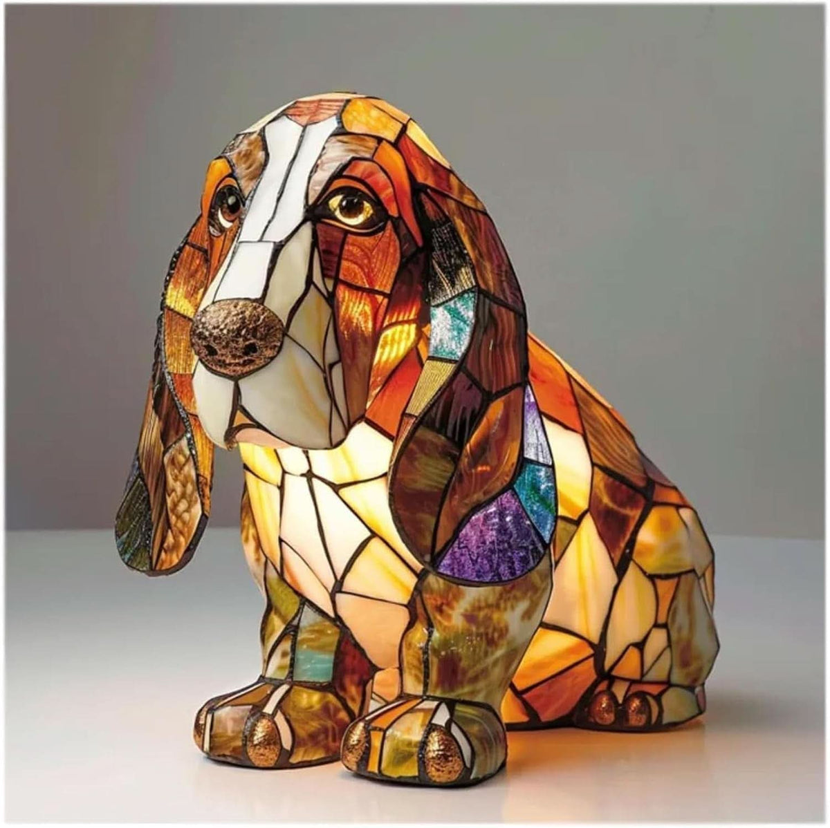 Seated basset hound lamp with long drooping ears and a bronze nose, lit from within in warm amber and brown glass. 2
