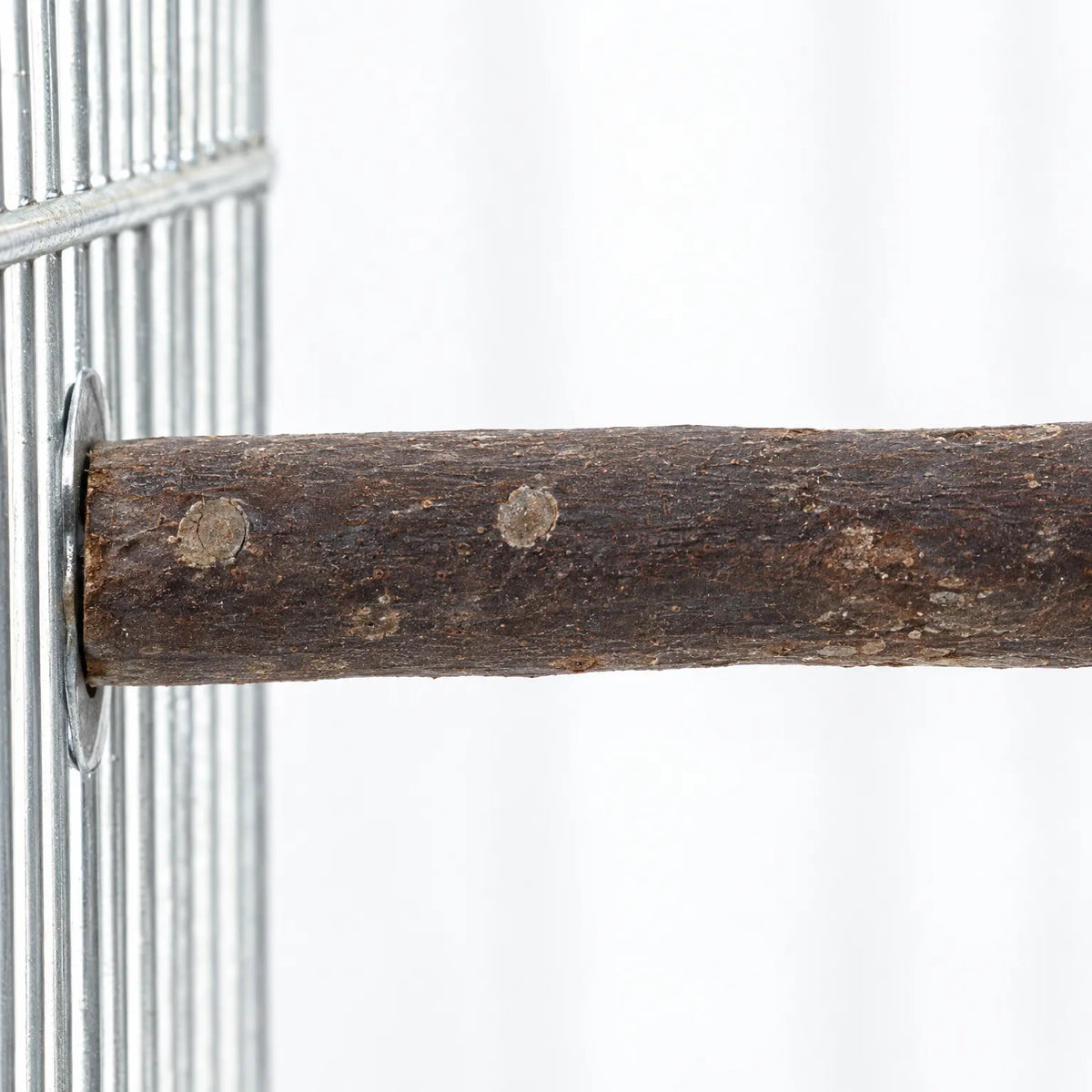 Close-up of a bark-covered wooden perch fixed to metal cage bars with a washer, showing small knots in the wood. 3