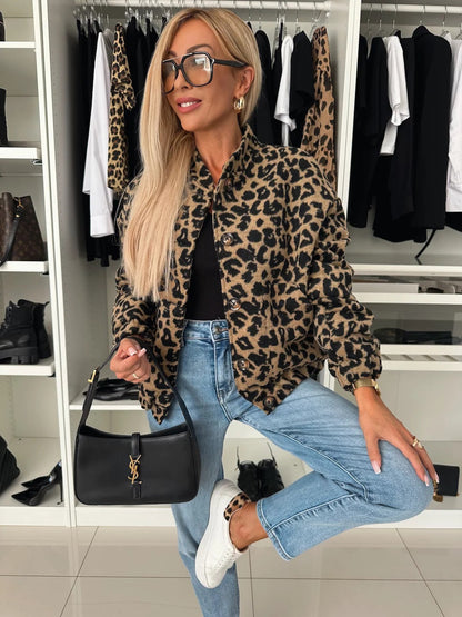Woman in the leopard print shacket with black top, jeans and white trainers, posing with one knee raised and a black handbag. 4