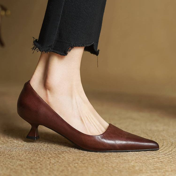 Side view of a brown leather pump on a model's foot, with black cropped trousers 19