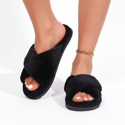 Model wearing black fluffy crossover slippers with open toes and thick black soles, one foot raised, with a gold chain anklet. 3