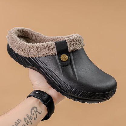 Hand holding a black clog with beige faux fur lining against a tan background 14