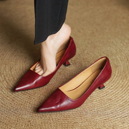 Model stepping into red leather kitten heels, wearing black trousers, on woven matting 8