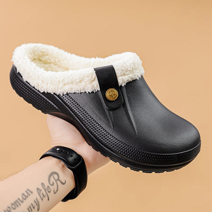 Hand holding a black clog with cream faux fur lining against a tan background 12