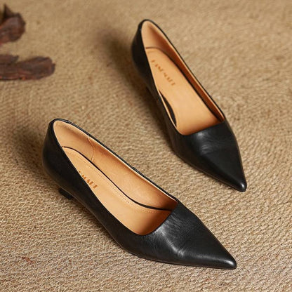 Pair of black leather pumps on woven matting showing the tan insoles 16