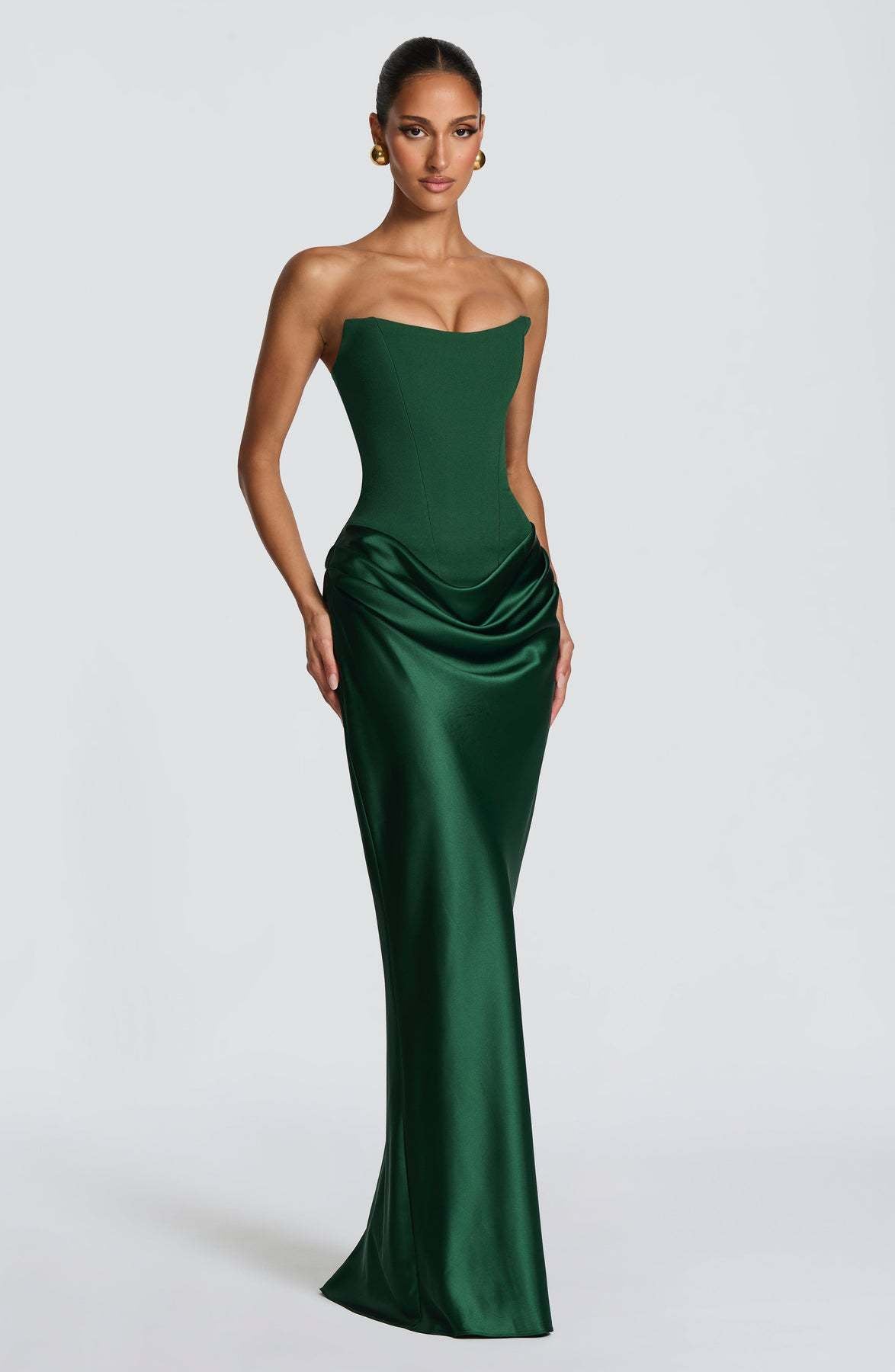 Emerald green strapless corset dress shown at a three-quarter angle, with one hand on hip 2