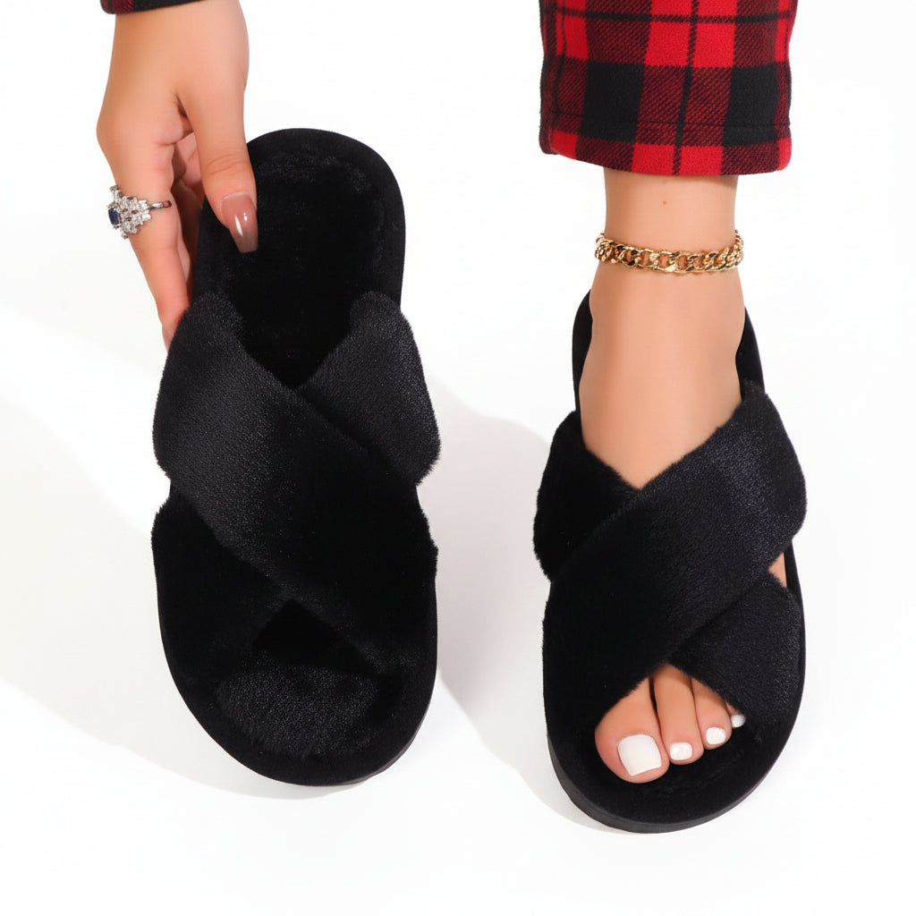 Black fluffy crossover slippers, one worn with red tartan trousers and the other held up to show the cushioned footbed. 9