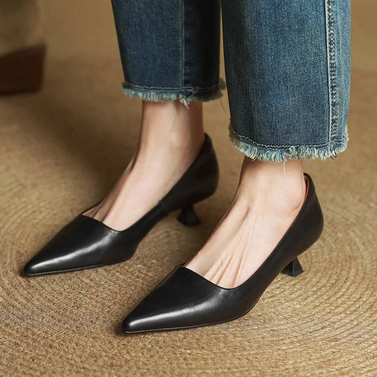 Black leather kitten heels worn by a model with frayed-hem jeans on woven matting 13