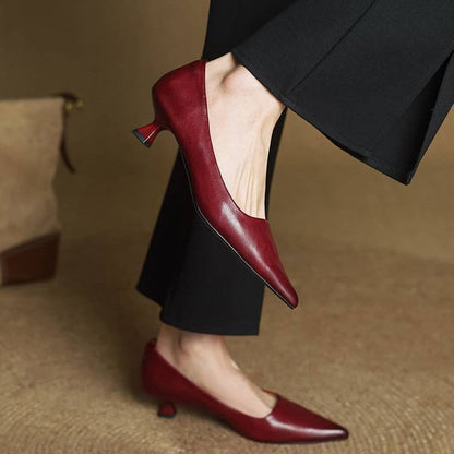 Red leather kitten heels worn with black flared trousers, one foot raised to show the heel 9